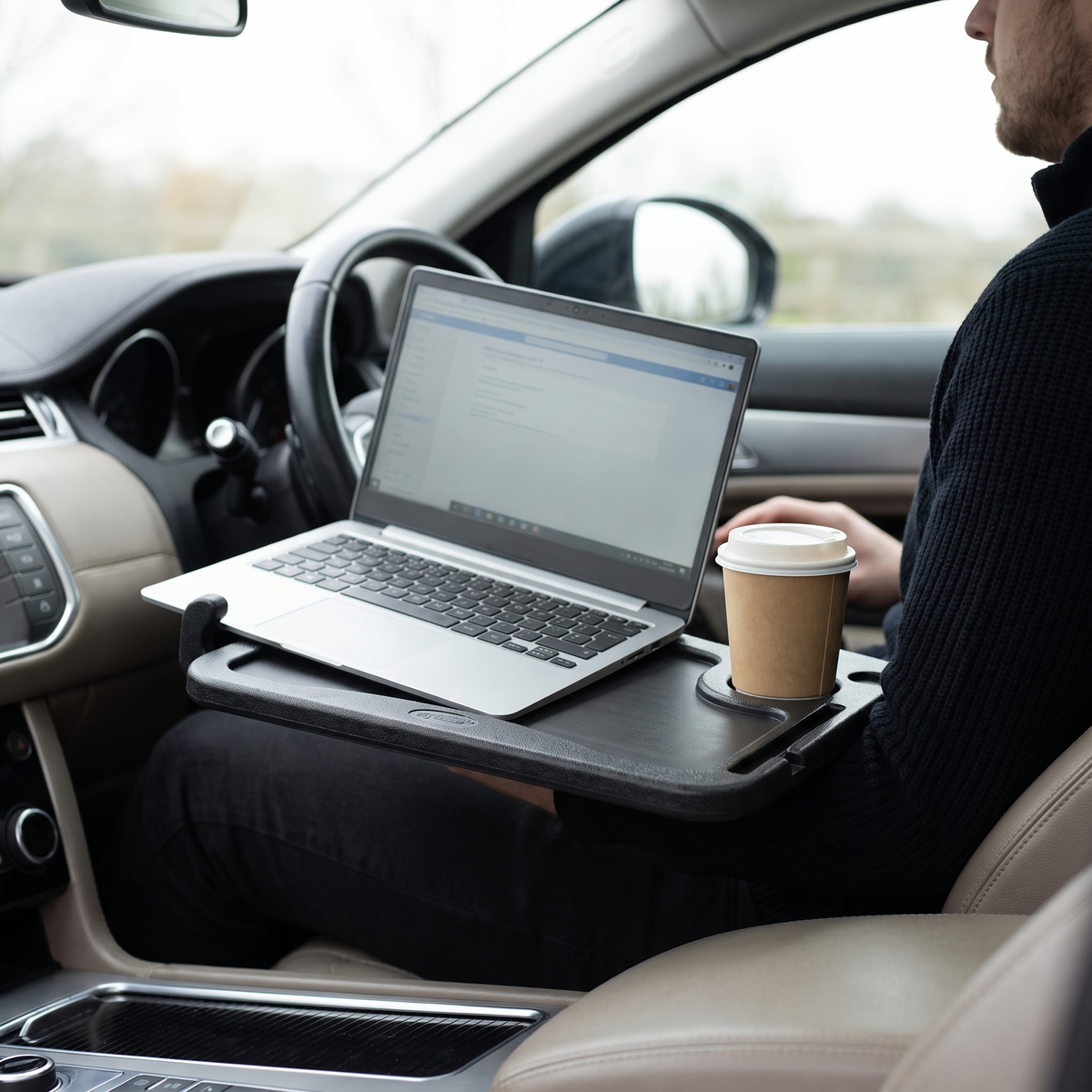 Steering wheel desk holding a laptop and coffee in a parked car