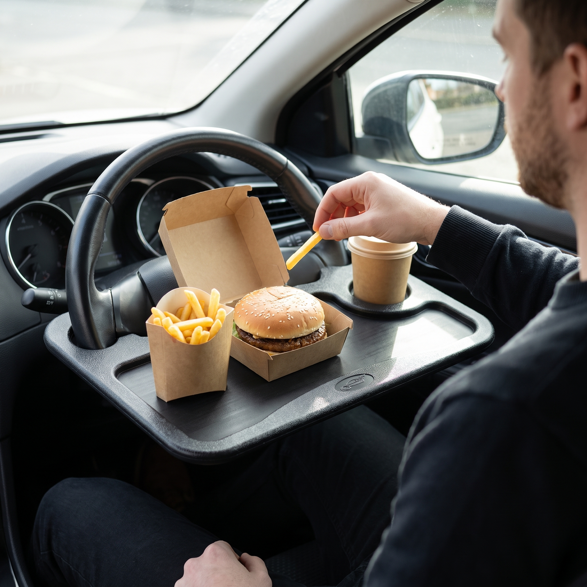 Eating a burger and chips off the steering wheel desk in a parked car